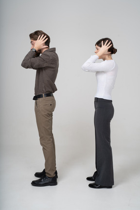 Vista lateral de um jovem casal com roupas de escritório tocando a cabeça