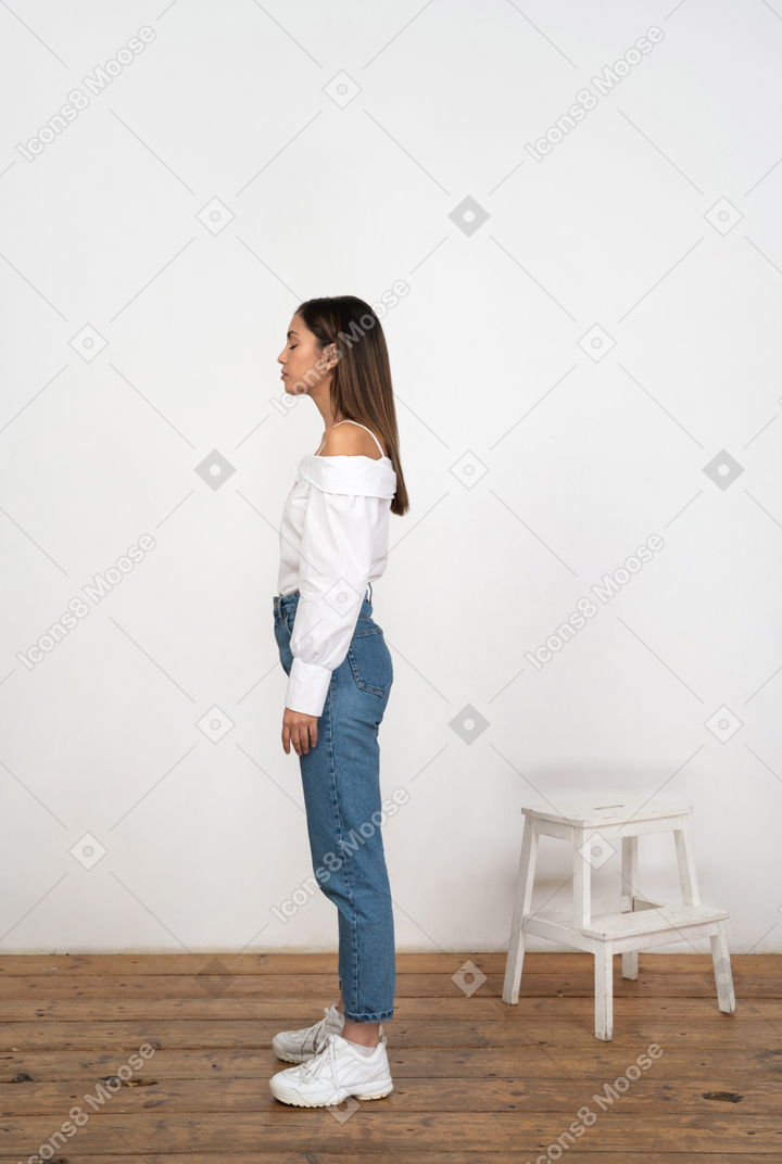 Woman in jeans and blouse standing in profile