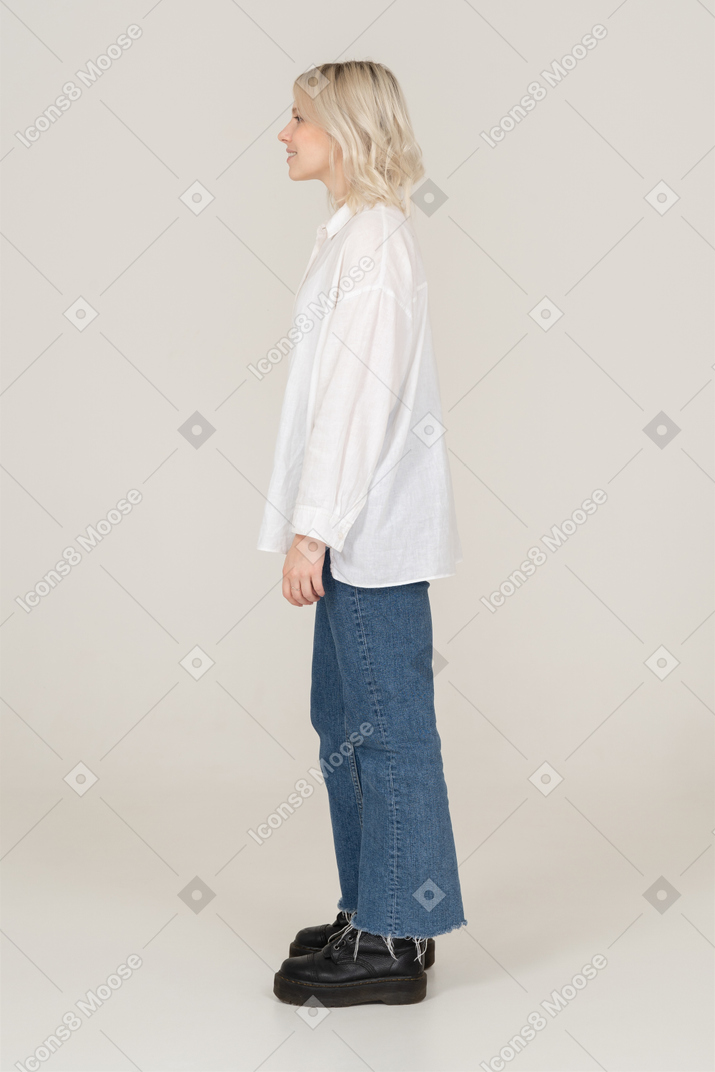 Side view of a blonde female in casual clothes standing still and looking aside
