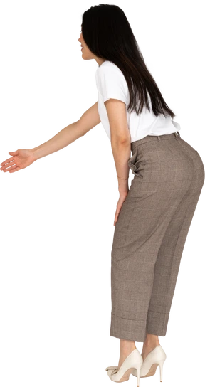 Side view of a young lady in breeches and t-shirt outstretching her hand and bending down