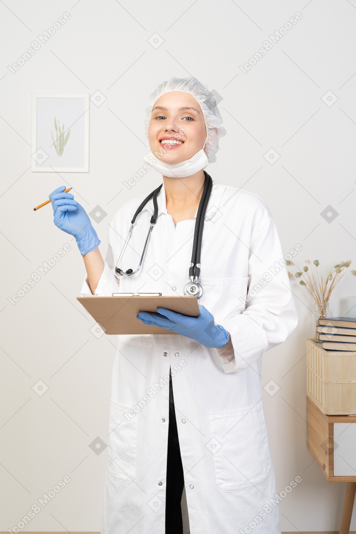 Vista frontal de una joven doctora tomando notas en su tableta