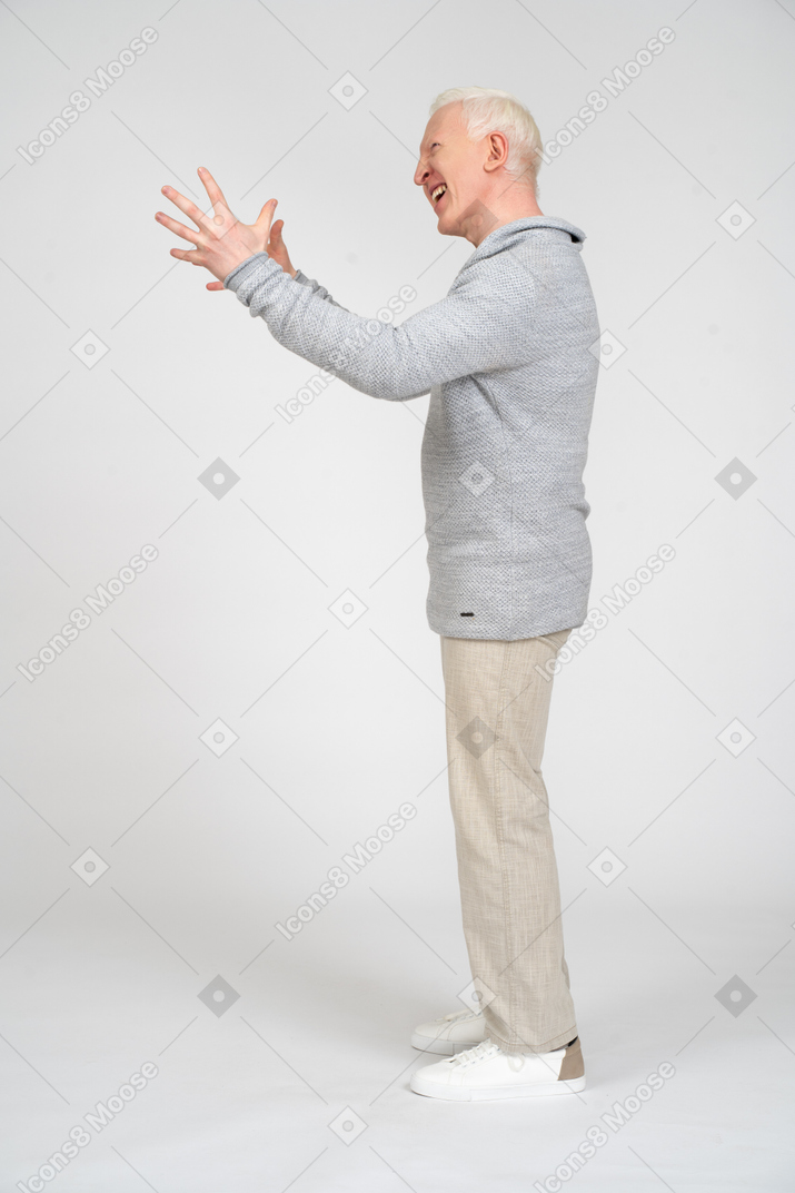 Vista laterale di un uomo in piedi e alzando le braccia con le dita aperte