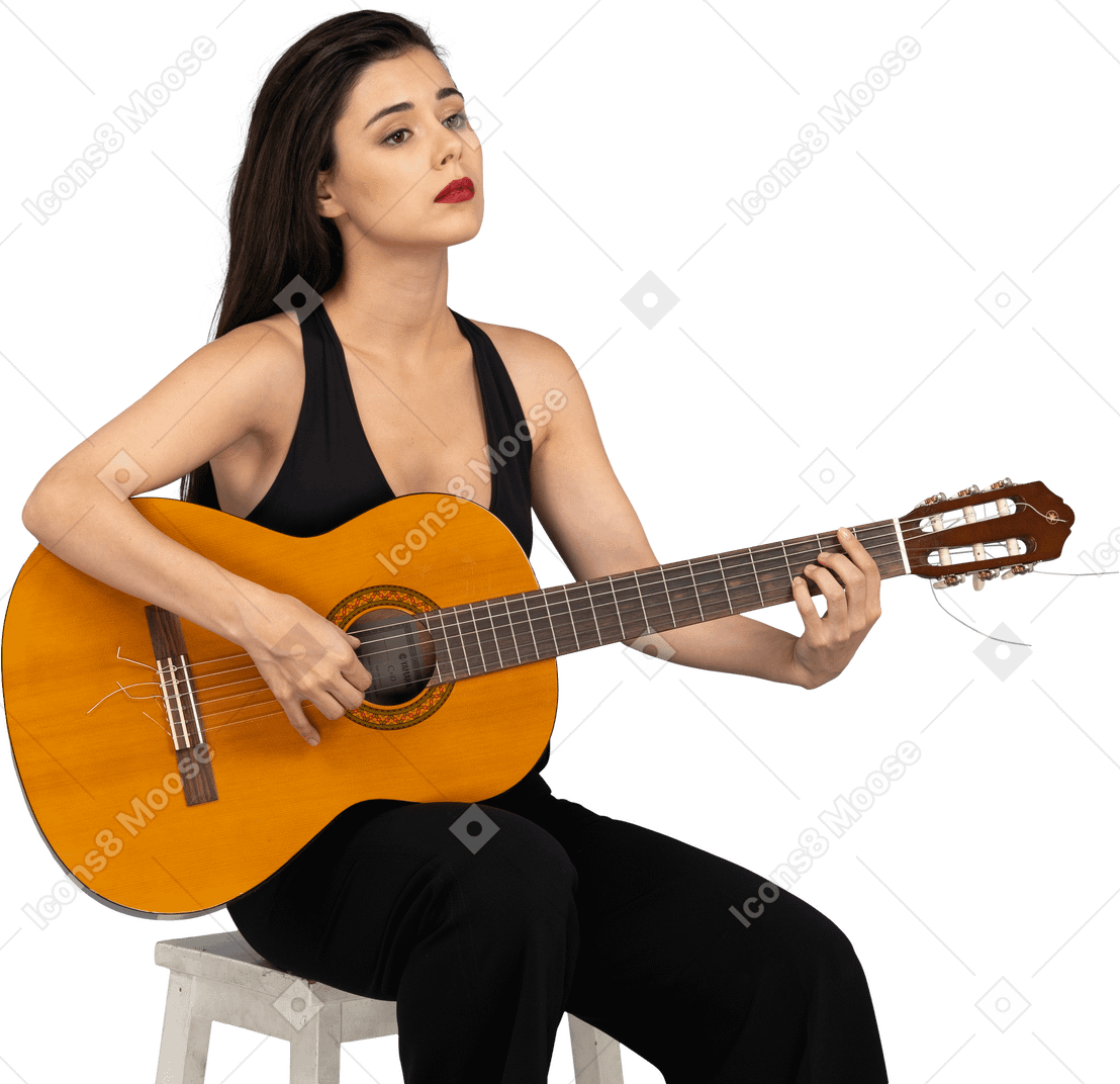 Вид в три четверти сидящей молодой леди в черном костюме, держащей гитару и поднимающей голову