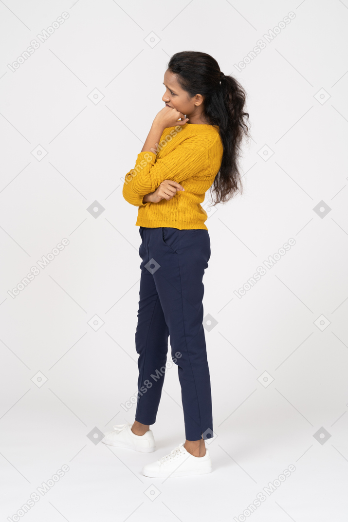 Vista laterale di una ragazza annoiata in abiti casual che tiene il pugno sul mento