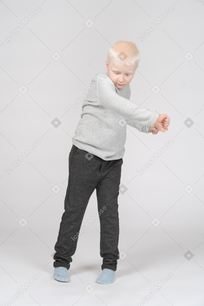 Vista frontal de un niño apretando los puños mientras mira hacia abajo