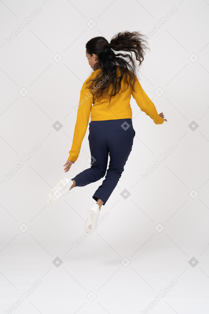점프하고 그녀의 발을 만지려고하는 캐주얼 옷을 입은 소녀의 후면보기