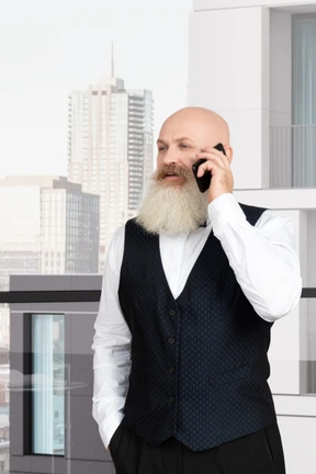 Elderly man speaking on the phone while standing on a balcony
