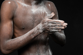 Close-up de um torso masculino todo em farinha juntando as palmas das mãos