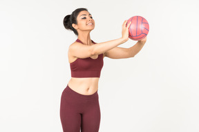 Young indian woman in sportswear is going to throw a ball