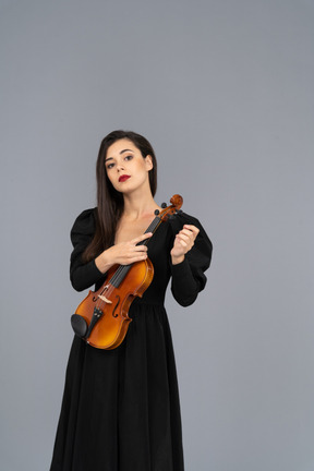 Vista frontale di una giovane donna in abito nero che tiene il violino