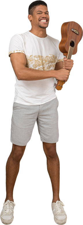 Front view of a man holding an ukulele like a bat