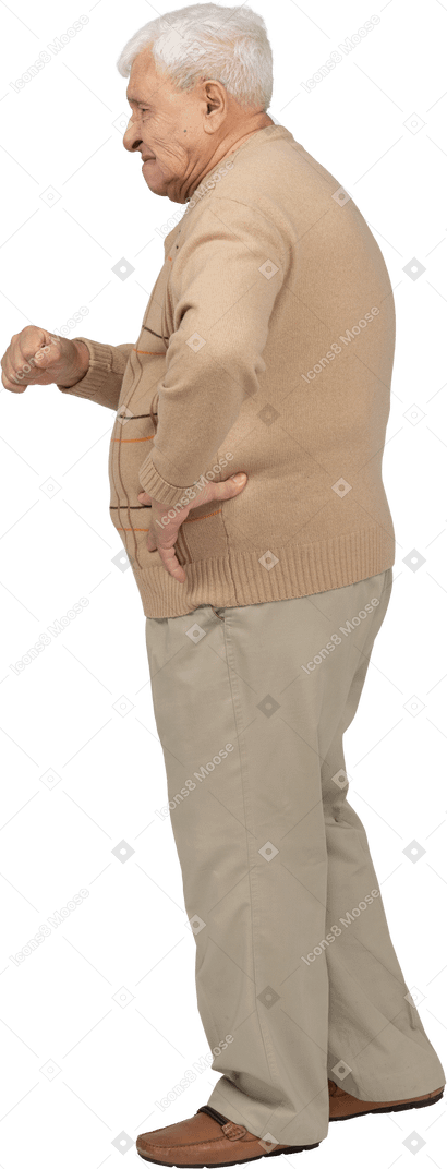 Side view of an angry old man in casual clothes standing with hand on hip