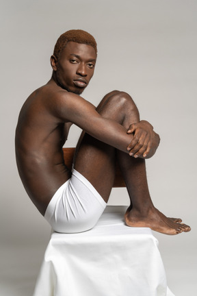A man in white underwear sitting on a table