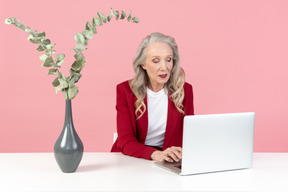 Femme âgée à la mode de travail sur ordinateur