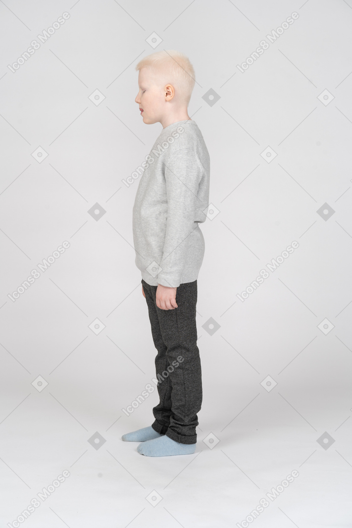 Side view of a kid boy in casual clothes looking down and opening mouth