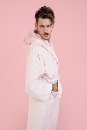 Handsome guy in pink robe standing with his hands in pockets