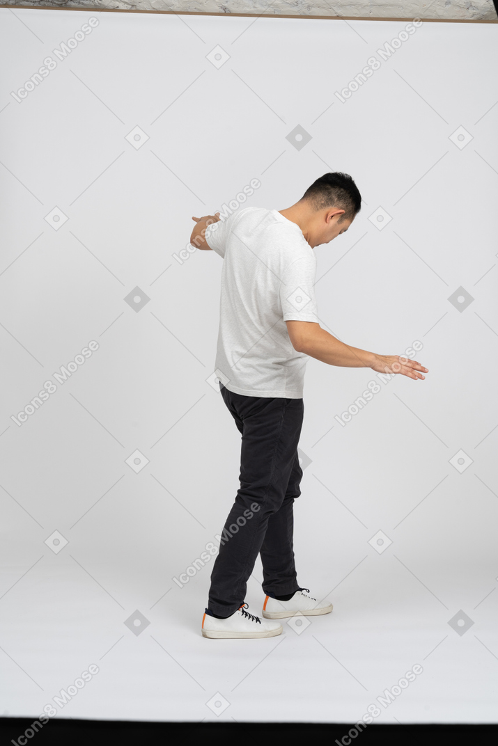 Vista lateral de un hombre con ropa informal caminando con los brazos extendidos
