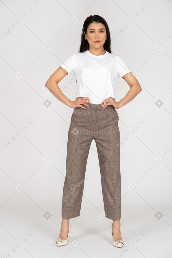 Front view of a young woman in breeches putting hands on hips
