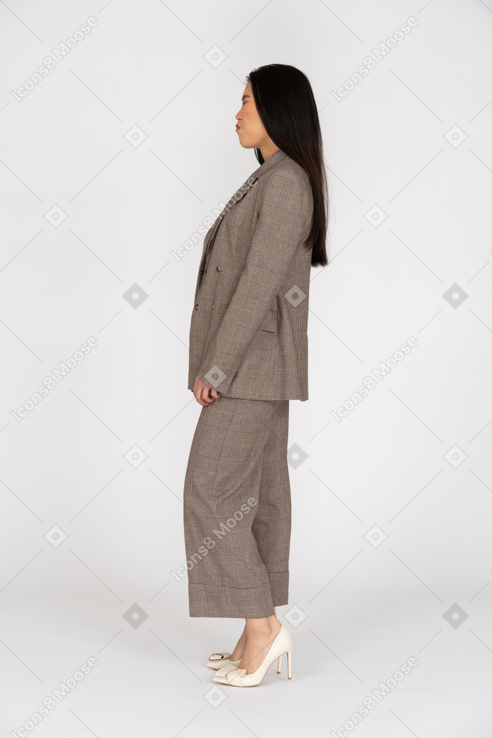 Side view of a pouting young lady in brown business suit closing her eyes