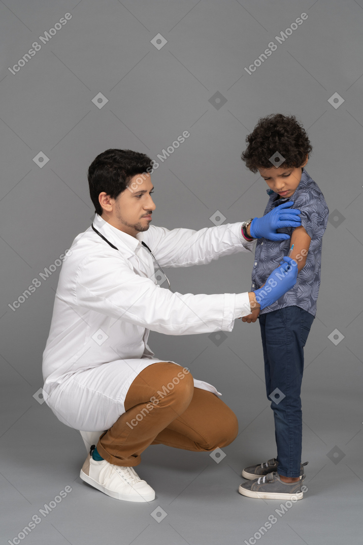 注射のために男の子を準備している医者