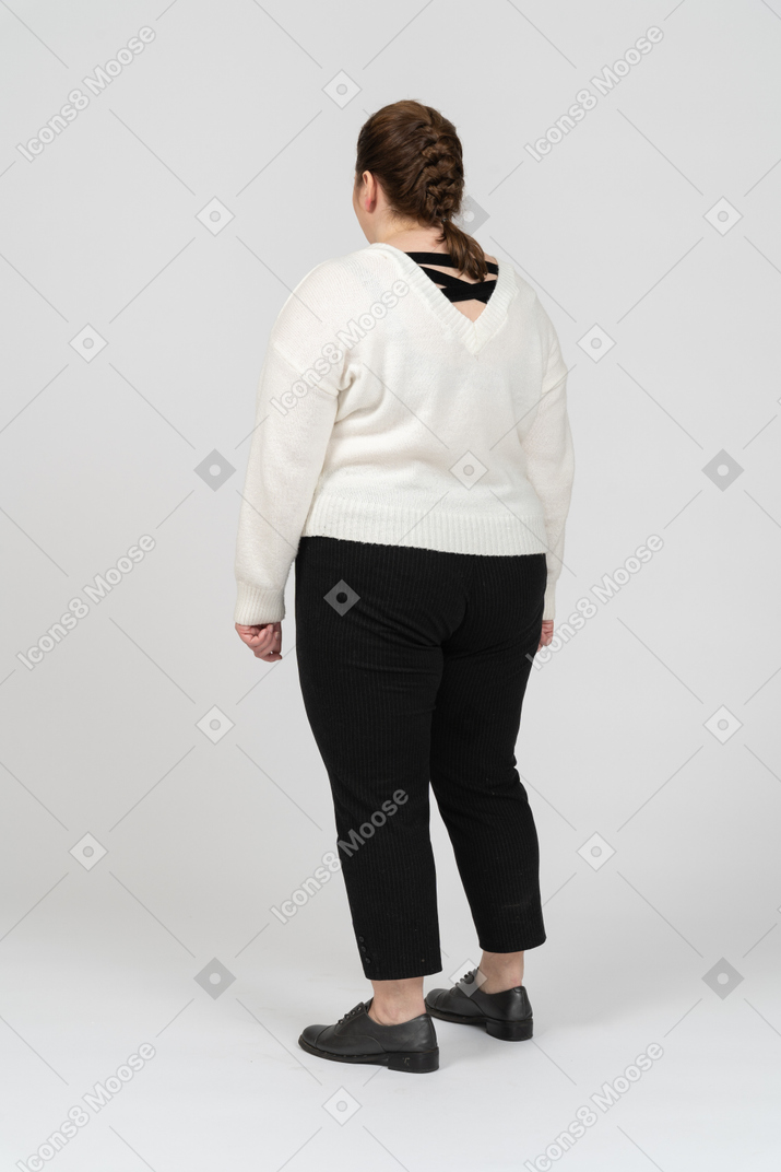 Plus size woman in white sweater standing