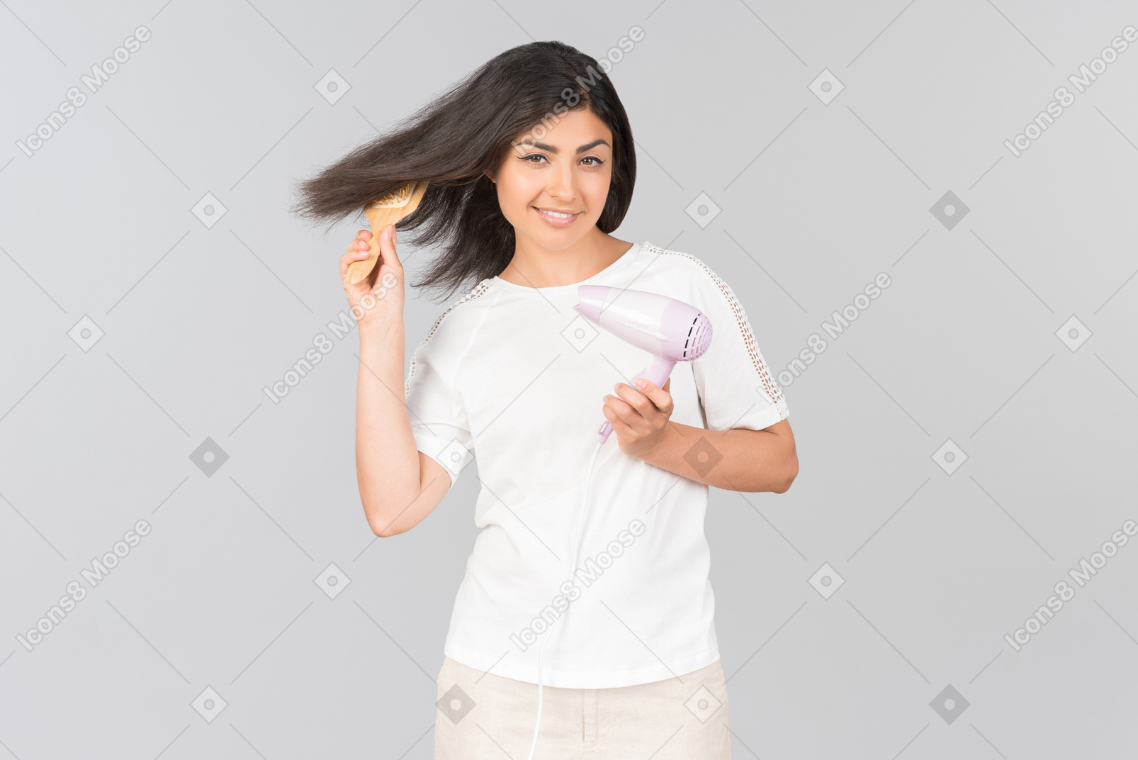 Joven mujer india peinarse con cepillo de pelo y secador de hierro