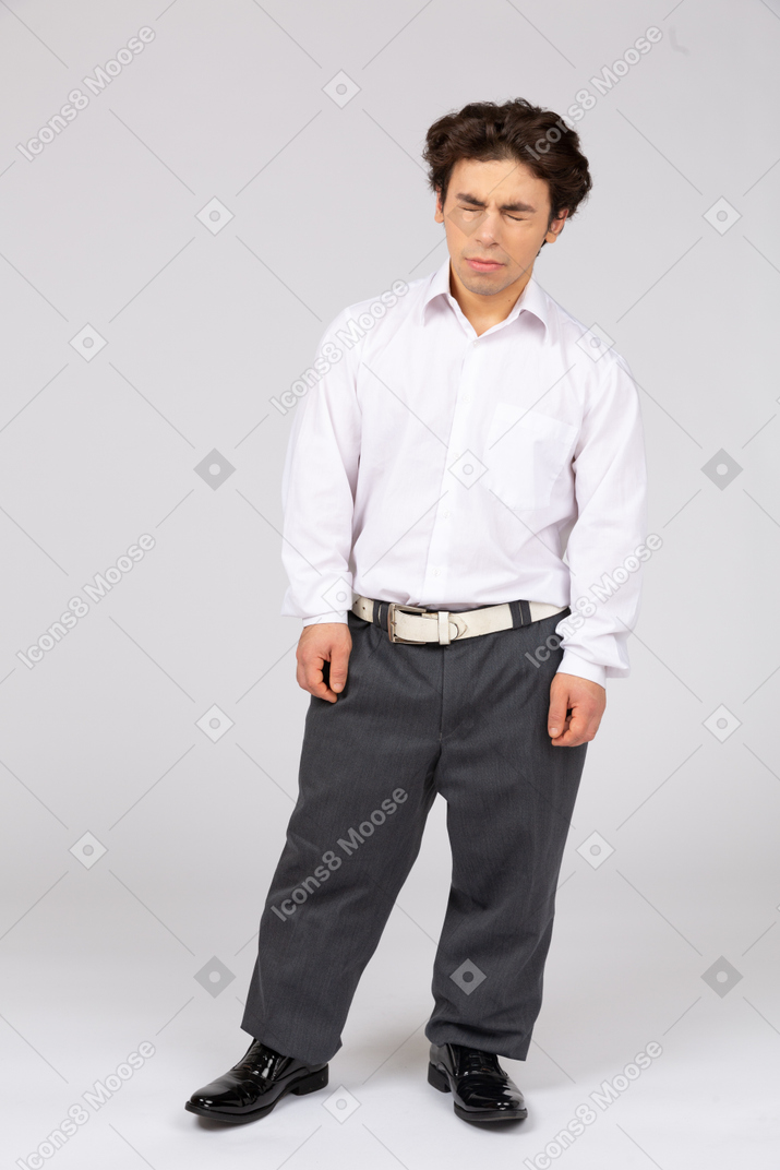 Young man in business casual clothes squeezing his eyes