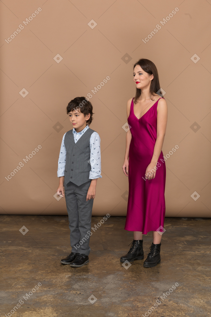 Woman in red dress and little boy standing in profile