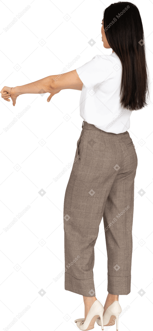 Vista posteriore di tre quarti di una giovane donna in calzoni e maglietta che mostra i pollici verso il basso