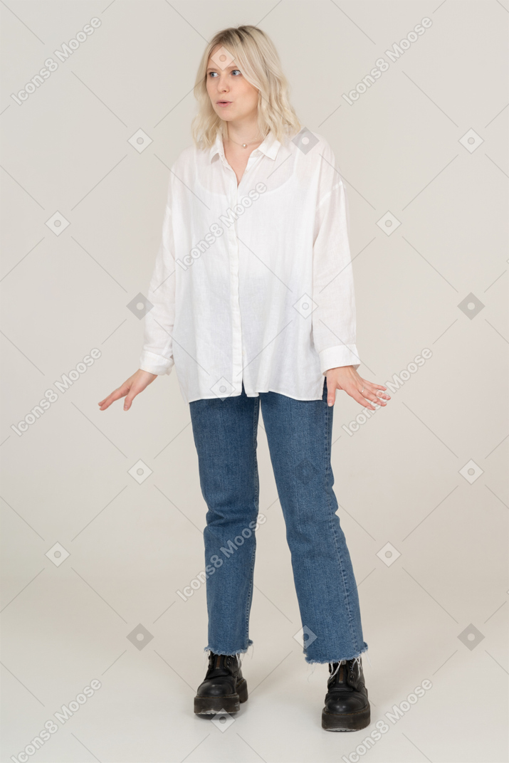 Vue de face d'une femme blonde surprise étendant les bras et regardant de côté