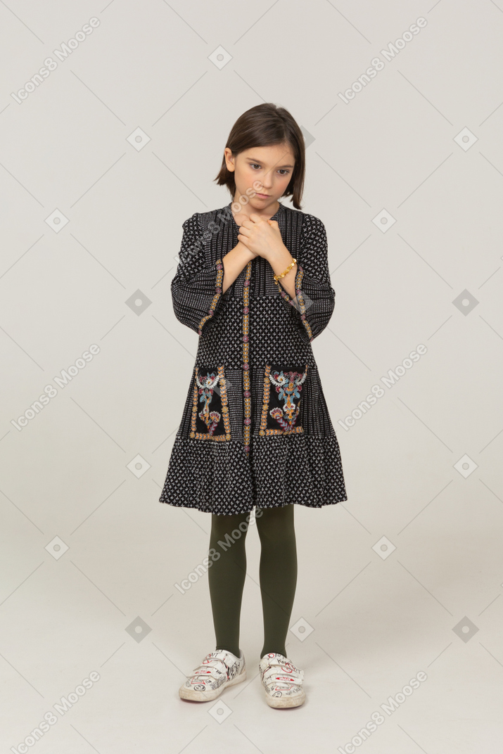Vista frontale di una bambina in abito che si tiene per mano insieme