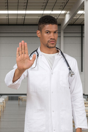 Man in a white lab coat showing stop hand gesture
