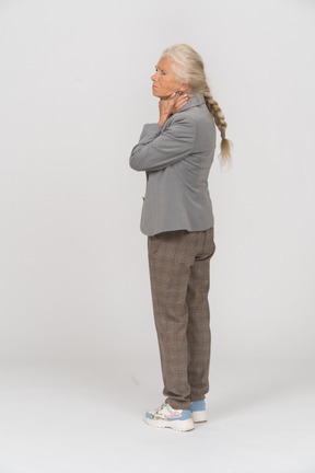 Side view of an old lady in suit touching her neck