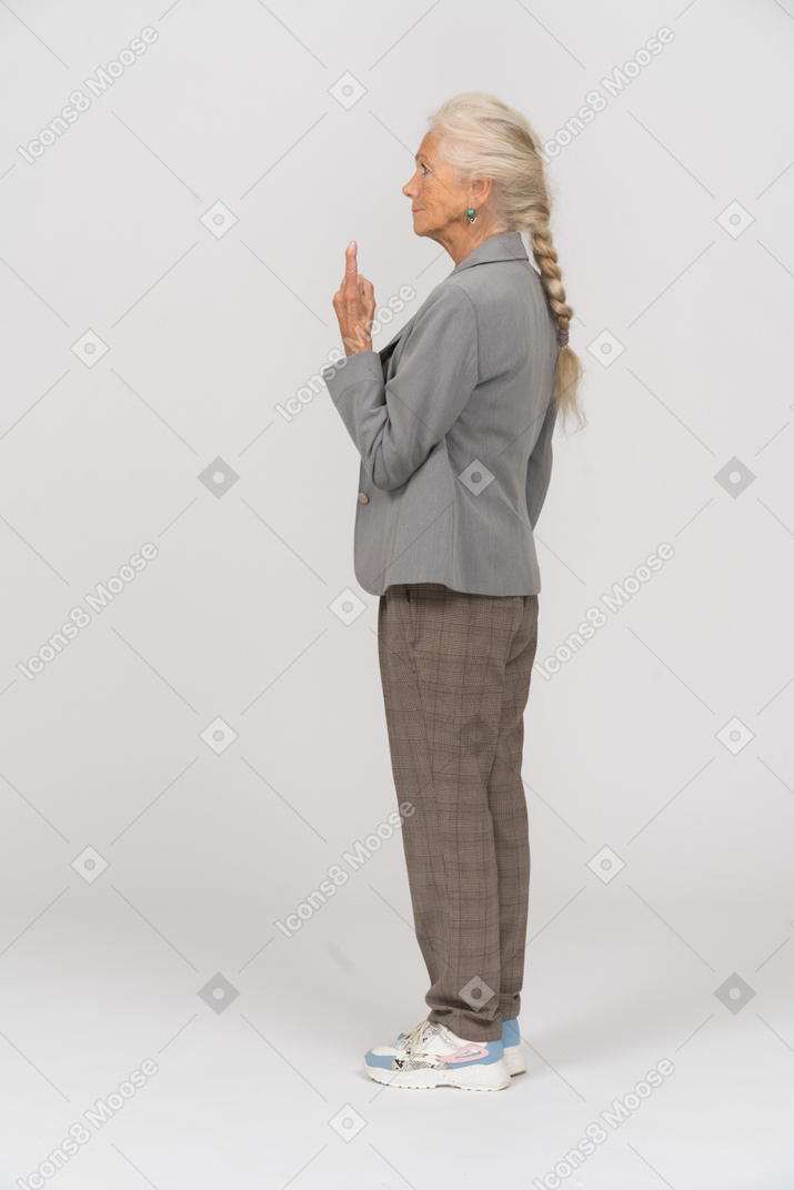 Side view of an old lady in suit pointing up with a finger
