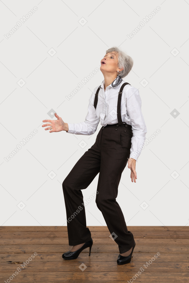 Three-quarter view of an astonished fashionable old lady bending knees while looking up