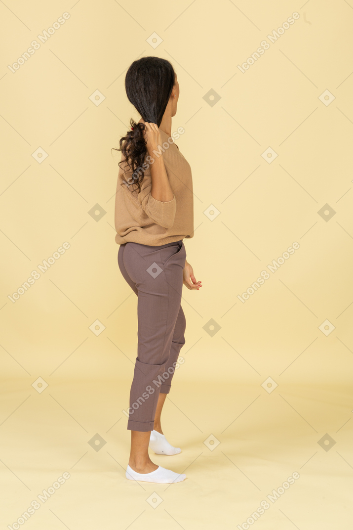 Back view of a dark-skinned young lady grabbing her hair