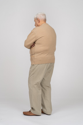 腕を組んで立っているカジュアルな服装の老人の背面図