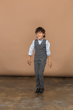 Vista frontal de um menino de terno cinza dançando