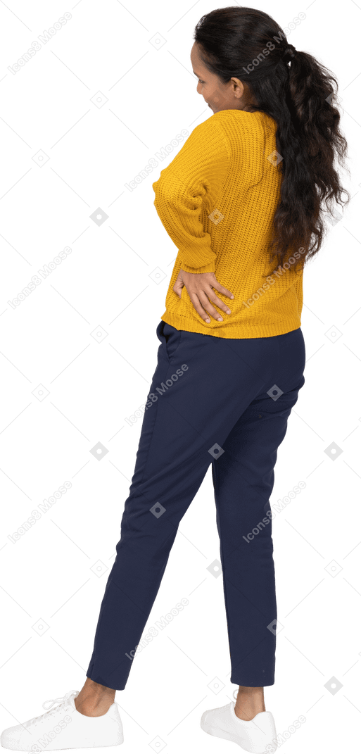 Back view of a girl in casual clothes posing with hand on hip