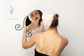 Young woman with bandaged head holding up a mirror