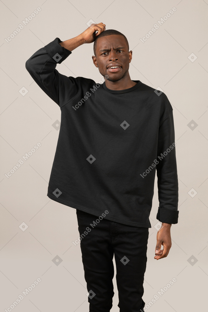 Confused young man scratching his head