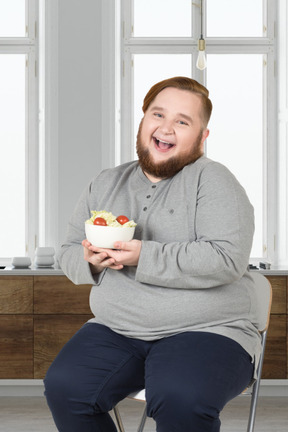 A man sitting on a chair holding a bowl of food