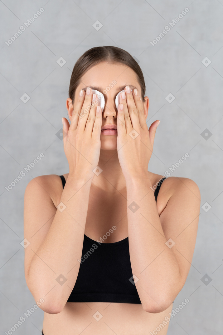 Mujer con almohadillas de algodón en los ojos