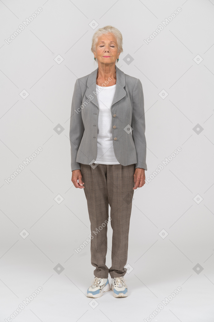 一个穿着西装、闭着眼睛站着的老妇人的前视图