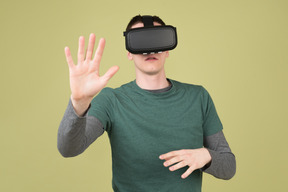 Un joven con casco de realidad virtual tocando algo