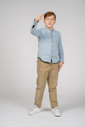 Young boy in blue shirt and khaki pants reaching toward camera