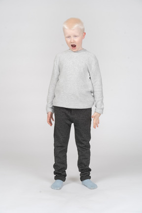 Front view of a boy standing and yawning