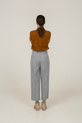 Back view of an offended young asian female in breeches and blouse crossing arms