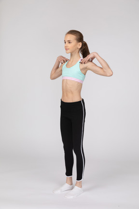 Vista de tres cuartos de una jovencita en ropa deportiva tocando sus hombros
