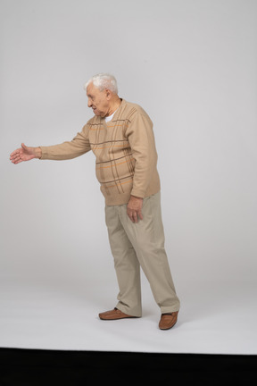 Вид сбоку на старика в повседневной одежде, протягивающего руку для рукопожатия